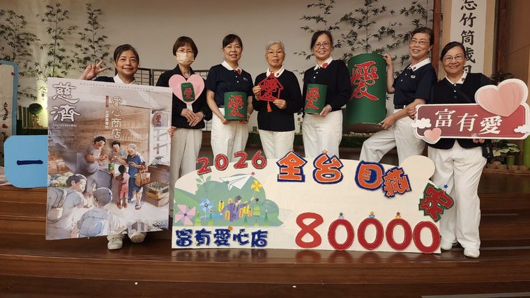 新店靜思堂「富有愛心店」聯誼會現場，志工與店家高舉「全臺八萬家」目標看板合影